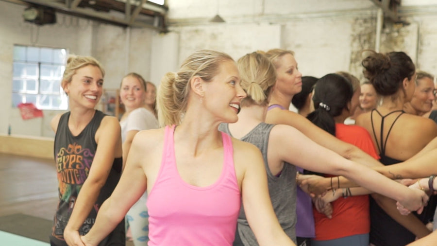 A child and adults smiling during a shared Rainbow Yoga group activity