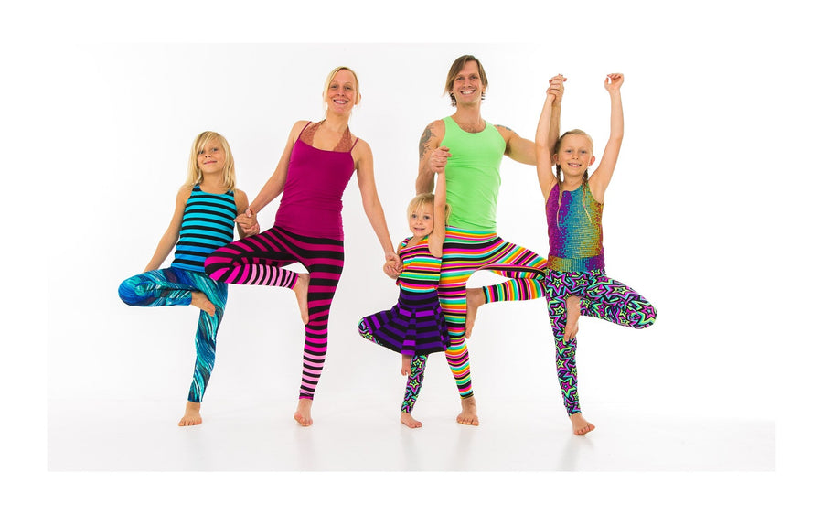 Adults and children holding hands in a playful standing balance, from the Rainbow Yoga photo archive.