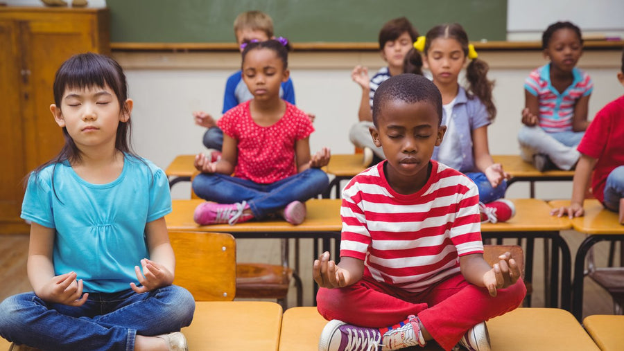 Diverse children practicing mindfulness in a Rainbow Yoga classroom setting