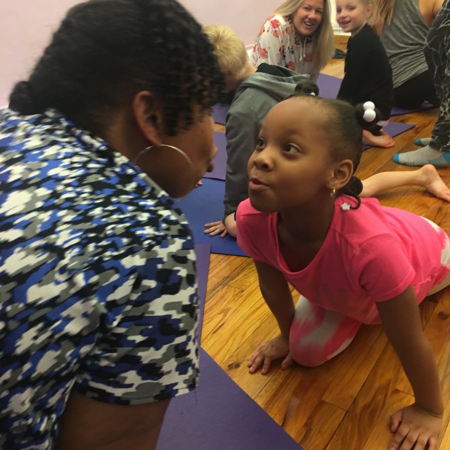 A child and adult sharing a playful Rainbow Yoga moment in class