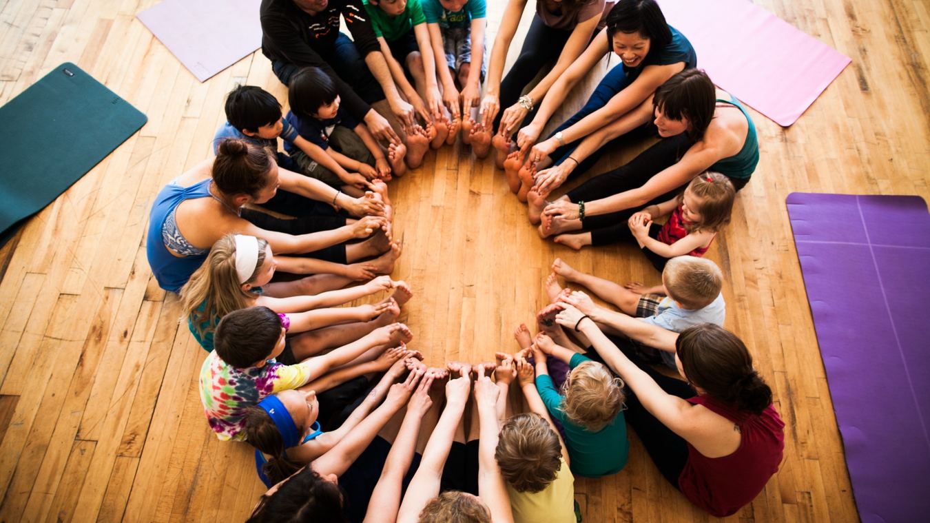 Children and families creating a joyful Rainbow Yoga circle together