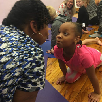 A child and adult sharing a playful Rainbow Yoga moment in class