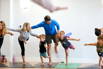 Adults and children building a playful family yoga shape