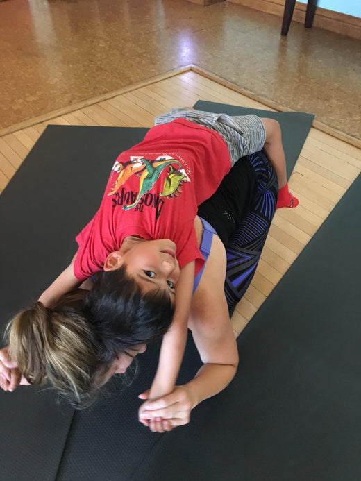 A child laughing during playful family yoga connection with Rainbow Yoga